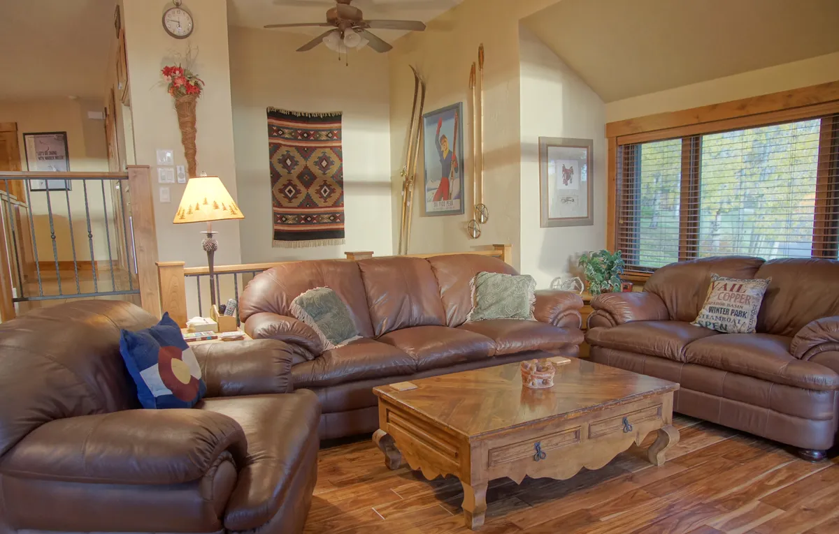 An inviting seating area with leather sofas, a wooden coffee table, and a decorative wall hanging, softly illuminated by a lamp. The setting feels intimate and perfect for reading, conversation, or enjoying peaceful evenings.